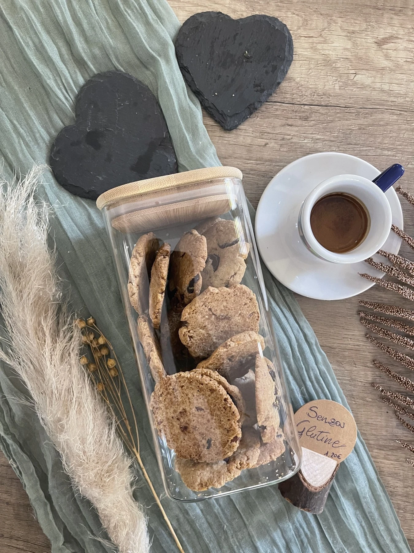 Biscotti senza glutine nel loro contenitore accanto a una tazzina di caffè